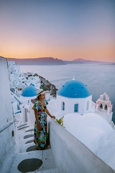 Puesta de sol en la isla de Santorini Grecia, hermoso pueblo encalado Oia con iglesia y molino de viento durante la puesta de sol Mujer en vacaciones de lujo Grecia — Foto de Stock