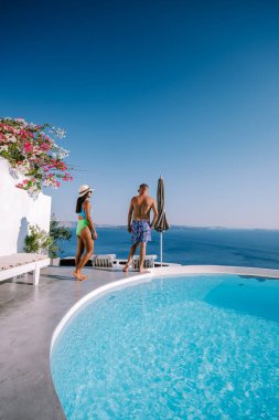 Santorini Yunanistan, genç çift güneş doğarken mavi kubbe kilisesi ve beyazlatılmış Oia Santorini köyünün gündoğumunu izlemek için Santorini Adası 'nda lüks bir tatile çıktılar.