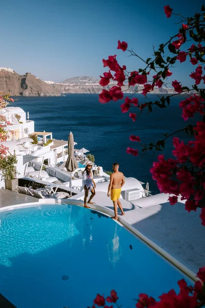 Santorini Grecia, pareja joven en vacaciones de lujo en la isla de Santorini viendo el amanecer por la iglesia de cúpula azul y el pueblo encalado de Oia Santorini Grecia durante el amanecer, hombres y mujeres en —  Fotos de Stock