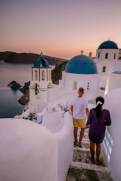 Santorini Griechenland, junges Paar im Luxusurlaub auf der Insel Santorini beim Sonnenaufgang an der blauen Kuppelkirche und dem weiß getünchten Dorf Oia Santorini Griechenland — Stockfoto