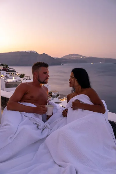 Santorini Griekenland, jong stel op luxe vakantie op het eiland Santorini kijken naar zonsopgang door de blauwe koepel kerk en witgekalkte dorp Oia Santorini Griekenland tijdens zonsopgang, mannen en vrouwen op — Stockfoto