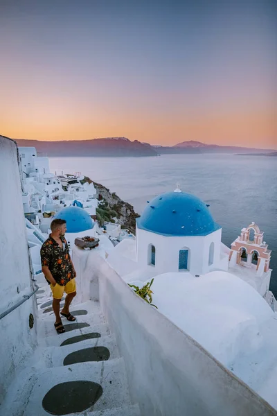Sonnenuntergang auf der Insel Santorin Griechenland, schönes weiß getünchtes Dorf Oia mit Kirche und Windmühle bei Sonnenuntergang, junge Männer im Luxusurlaub Santorin — Stockfoto