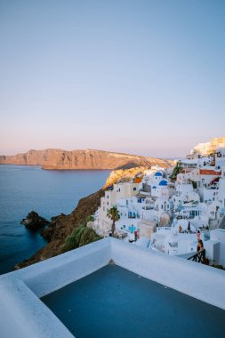 Yunanistan 'ın Santorini Adası' nda gün batımı, güzel, bembeyaz bir köy olan Oia 'da gün batımında kilise ve yel değirmeni.