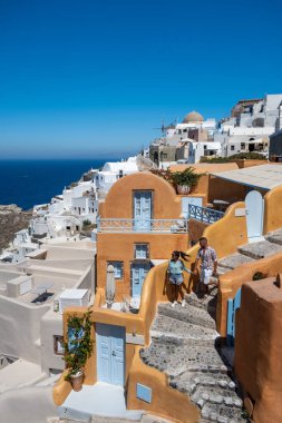 Santorini Yunanistan, genç çift güneş doğarken mavi kubbe kilisesi ve beyazlatılmış Oia Santorini köyünün gündoğumunu izlemek için Santorini Adası 'nda lüks bir tatile çıktılar.