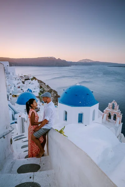 Santorini Grecia, giovane coppia in vacanza di lusso all'isola di Santorini guardando l'alba dalla chiesa cupola blu e villaggio imbiancato di Oia Santorini Grecia durante l'alba, uomini e donne su — Foto Stock