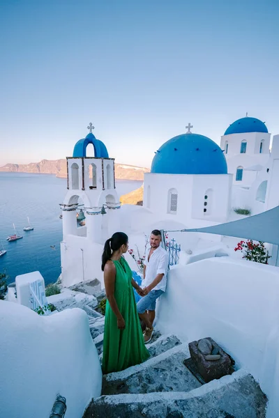 Santorini Griechenland, junges Paar im Luxusurlaub auf der Insel Santorini beim Sonnenaufgang an der blauen Kuppelkirche und dem weiß getünchten Dorf Oia Santorini Griechenland, Männer und Frauen bei Sonnenaufgang — Stockfoto