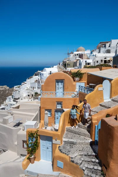 Santorini Griechenland, junges Paar im Luxusurlaub auf der Insel Santorini beim Sonnenaufgang an der blauen Kuppelkirche und dem weiß getünchten Dorf Oia Santorini Griechenland, Männer und Frauen bei Sonnenaufgang — Stockfoto