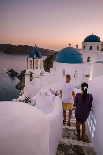 Santorini Grecia, giovane coppia in vacanza di lusso all'isola di Santorini guardando l'alba presso la chiesa cupola blu e il villaggio imbiancato di Oia Santorini Grecia durante l'alba — Foto Stock