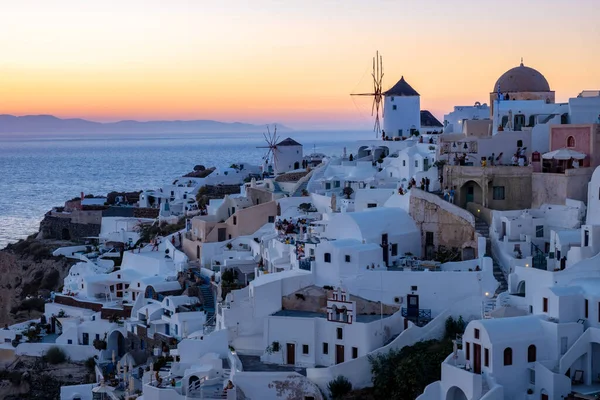 Solnedgång på ön Santorini Grekland, vackra vitkalkade byn Oia med kyrka och väderkvarn under solnedgången — Stockfoto