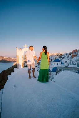 Santorini Yunanistan, genç çift güneş doğarken mavi kubbe kilisesi ve beyazlatılmış Oia Santorini köyünün gündoğumunu izlemek için Santorini Adası 'nda lüks bir tatile çıktılar.