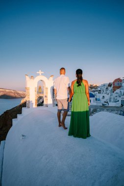 Santorini Yunanistan, genç çift güneş doğarken mavi kubbe kilisesi ve beyazlatılmış Oia Santorini köyünün gündoğumunu izlemek için Santorini Adası 'nda lüks bir tatile çıktılar.