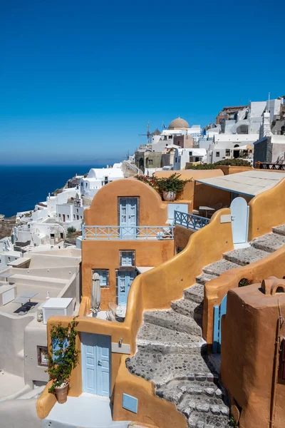 Santorini, Yunanistan. Önünde çiçekler olan küçük caddedeki geleneksel Kiklad Santorini evlerinin resimli görüntüsü. Konum: Oia Köyü, Santorini, Yunanistan. Tatil arkaplanı.