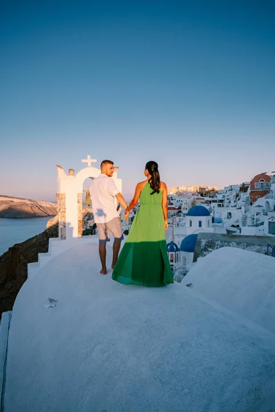 Santorini Grecia, giovane coppia in vacanza di lusso all'isola di Santorini guardando l'alba dalla chiesa cupola blu e villaggio imbiancato di Oia Santorini Grecia durante l'alba, uomini e donne su — Foto Stock