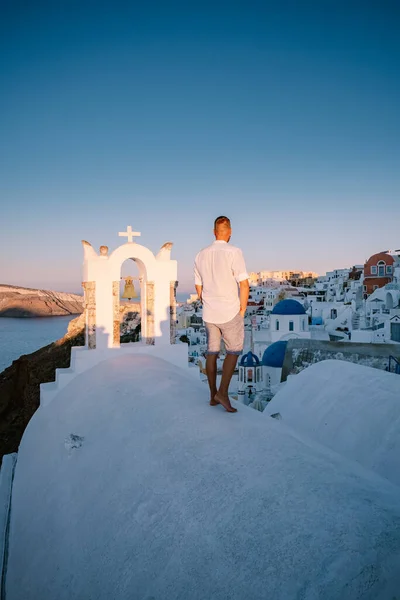 Sunset at the Island Of Santorini Greece, beautiful whitewashed village Oia with church and windmill during sunset, young men on luxury vacation Santorini — Stock Photo, Image