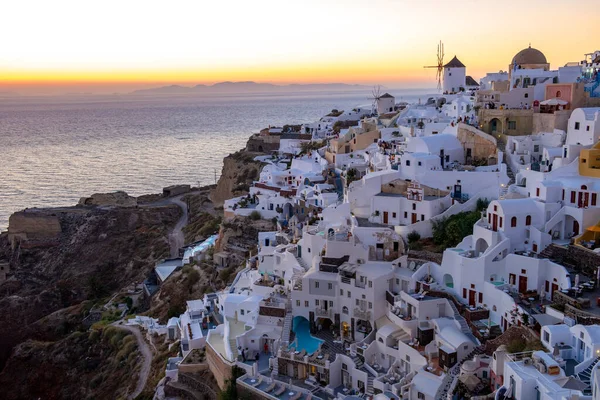 Solnedgång på ön Santorini Grekland, vackra vitkalkade byn Oia med kyrka och väderkvarn under solnedgången — Stockfoto