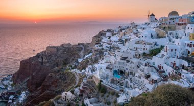 Yunanistan 'ın Santorini Adası' nda gün batımı, güzel, bembeyaz bir köy olan Oia 'da gün batımında kilise ve yel değirmeni.