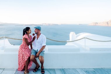 Santorini Yunanistan, genç çift güneş doğarken mavi kubbe kilisesi ve beyazlatılmış Oia Santorini köyünün gündoğumunu izlemek için Santorini Adası 'nda lüks bir tatile çıktılar.