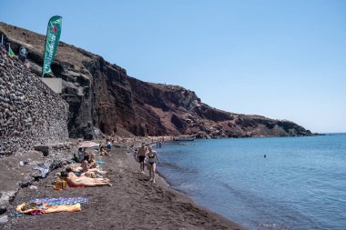 Santorini Yunanistan Ağustos 2020, Santorini plajı yaz günü güneşlenen insanlarla dolu.