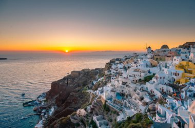 Yunanistan 'ın Santorini Adası' nda gün batımı, güzel, bembeyaz bir köy olan Oia 'da gün batımında kilise ve yel değirmeni.