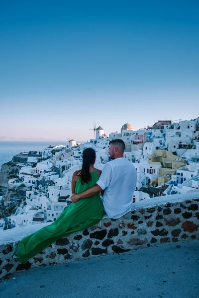 Santorini Grecia, giovane coppia in vacanza di lusso all'isola di Santorini guardando l'alba dalla chiesa cupola blu e villaggio imbiancato di Oia Santorini Grecia durante l'alba, uomini e donne su — Foto Stock