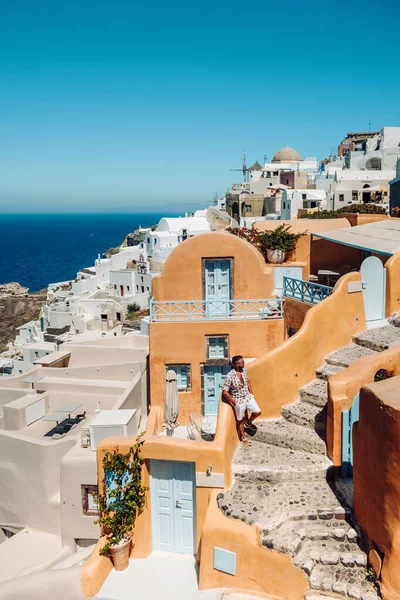 Santorini Griechenland, junger Mann im Luxusurlaub auf der Insel Santorini, der den Sonnenaufgang an der blauen Kuppelkirche und dem weiß getünchten Dorf Oia Santorini Griechenland bei Sonnenaufgang beobachtet, Männer und Frauen auf — Stockfoto