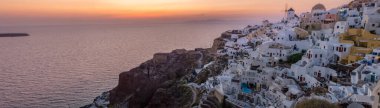 Yunanistan 'ın Santorini Adası' nda gün batımı, güzel, bembeyaz bir köy olan Oia 'da gün batımında kilise ve yel değirmeni.