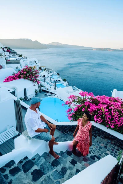 Santorini Greece, young couple on luxury vacation at the Island of Santorini watching sunrise by the blue dome church and whitewashed village of Oia Santorini Greece during sunrise, men and woman on — Stock Photo, Image