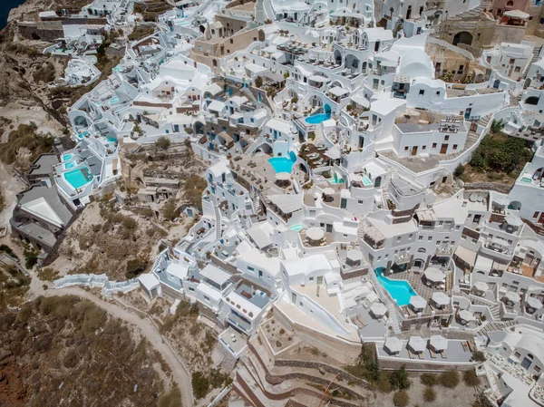 Drone vista sobre Santorini, vista aérea sobre a aldeia caiada de branco de Oia com resort de férias de luxo com piscinas infinitas em Santorini Grécia — Fotografia de Stock
