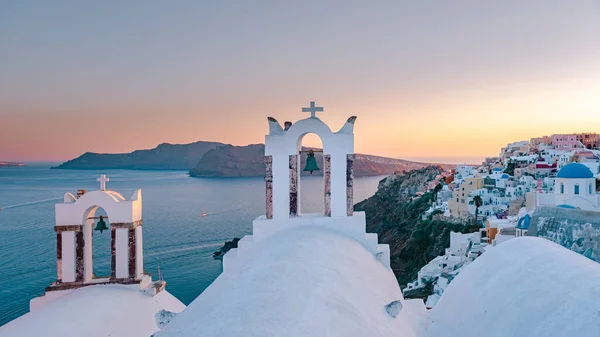 Puesta de sol en la isla de Santorini Grecia, hermoso pueblo encalado Oia con iglesia y molino de viento durante la puesta del sol — Foto de Stock
