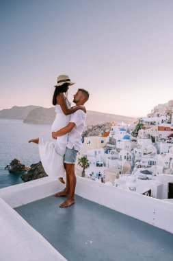 Santorini Yunanistan, Santorini Adası 'nda lüks tatilde olan genç bir çift mavi kubbe kilisesi ve beyazlatılmış Oia Santorini Yunanistan köyünün doğuşunu izliyor. 