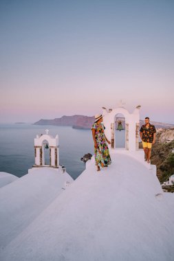 Santorini Yunanistan, Santorini Adası 'nda lüks tatilde olan genç bir çift mavi kubbe kilisesi ve beyazlatılmış Oia Santorini Yunanistan köyünün doğuşunu izliyor. 