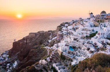 Yunanistan 'ın Santorini Adası' nda gün batımı, güzel, bembeyaz bir köy olan Oia 'da gün batımında kilise ve yel değirmeni.