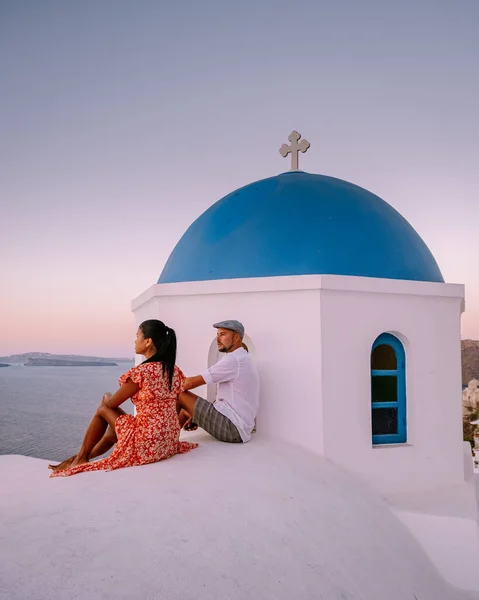 Santorin Grèce, jeune couple en vacances de luxe à l'île de Santorin regardant le lever du soleil près de l'église à dôme bleu et village blanchi à la chaux d'Oia Santorin Grèce — Photo