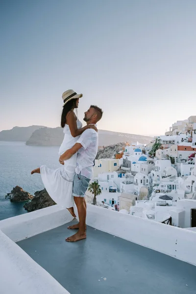 Santorini Grecia, giovane coppia in vacanza di lusso sull'isola di Santorini guardando l'alba vicino alla chiesa a cupola blu e al villaggio imbiancato di Oia Santorini Grecia — Foto Stock