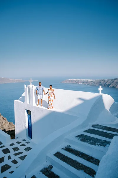 Para odwiedza Skaros rock Fira, Santorini Grecja, młoda para na luksusowych wakacjach na wyspie Santorini oglądając wschód słońca przy błękitnej kopule kościoła i bielonej miejscowości Oia Santorini Grecja — Zdjęcie stockowe