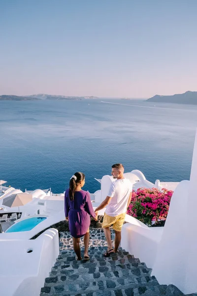 Santorini Greece, young couple on luxury vacation at the Island of Santorini watching sunrise by the blue dome church and whitewashed village of Oia Santorini Greece — Stock Photo, Image