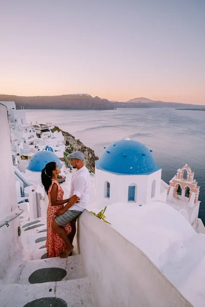 Santorini Griechenland, junges Paar im Luxusurlaub auf der Insel Santorini beim Sonnenaufgang an der blauen Kuppelkirche und dem weiß getünchten Dorf Oia Santorini Griechenland — Stockfoto