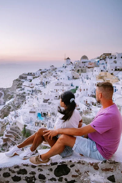 Santorini Greece, young couple on luxury vacation at the Island of Santorini watching sunrise by the blue dome church and whitewashed village of Oia Santorini Greece — Stock Photo, Image