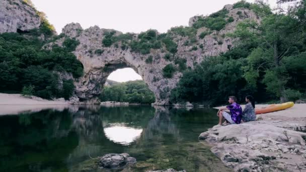 Couple sur la plage au bord de la rivière dans l'Ardèche France Pont d'Arc, Ardèche France, vue de l'arche Narural à Vallon Pont Darc dans le canyon de l'Ardèche en France Europe — Video
