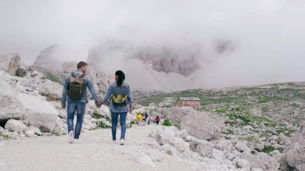 Sisli havalarda İtalyan dolomitlerinde yürüyüşe çıkan çift, İtalya 'nın Dolomites kentindeki Tre Cime zirvelerine sersemletici bir manzara sergiliyor. Tre Cime di Lavaredo, Drei zinnen — Stok video