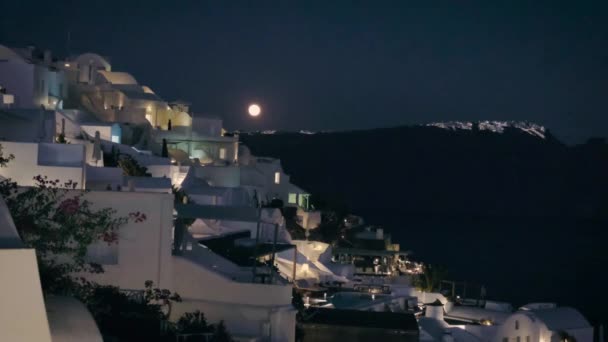 Moonrise στο νησί της Σαντορίνης Ελλάδα, όμορφο ασβεστωμένο χωριό της Οίας με εκκλησία και ανεμόμυλο κατά τη διάρκεια του ηλιοβασιλέματος, δρόμους της Οίας Σαντορίνης κατά τη διάρκεια των καλοκαιρινών διακοπών στο ελληνικό νησί — Αρχείο Βίντεο