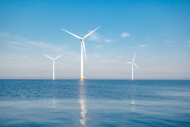 Fırtınalı bulutları, mavi gökyüzü ve okyanustaki yel değirmeni parkı olan açık deniz yel değirmeni parkı.