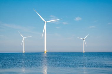 Fırtınalı bulutları, mavi gökyüzü ve okyanustaki yel değirmeni parkı olan açık deniz yel değirmeni parkı.