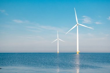Fırtınalı bulutları, mavi gökyüzü ve okyanustaki yel değirmeni parkı olan açık deniz yel değirmeni parkı.