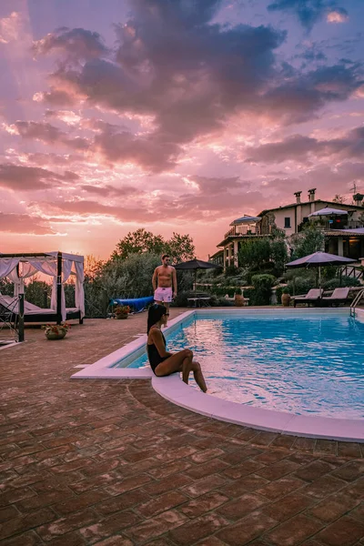 Розкішний заміський будинок з басейном в Італії, пара з відпустки на розкішному віллі в Італії, чоловіки і жінки дивляться захід сонця — стокове фото