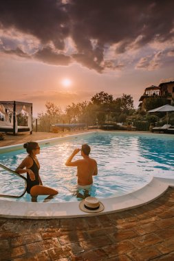 İtalya 'da yüzme havuzlu lüks kır evi, İtalya' da tatil yapan çift, gün batımını izleyen erkek ve kadın.