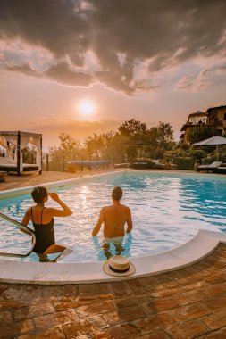 İtalya 'da yüzme havuzlu lüks kır evi, İtalya' da tatil yapan çift, gün batımını izleyen erkek ve kadın.