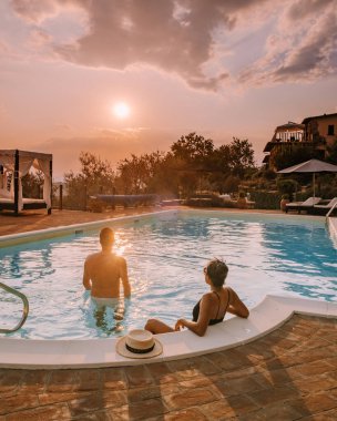 İtalya 'da yüzme havuzlu lüks kır evi, İtalya' da tatil yapan çift, gün batımını izleyen erkek ve kadın.