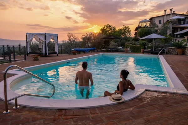 İtalya 'da yüzme havuzlu lüks kır evi, İtalya' da tatil yapan çift, gün batımını izleyen erkek ve kadın.
