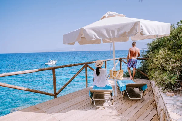 Pareja por el océano en la cama de sol por el océano en la playa de Creta Grecia — Foto de Stock